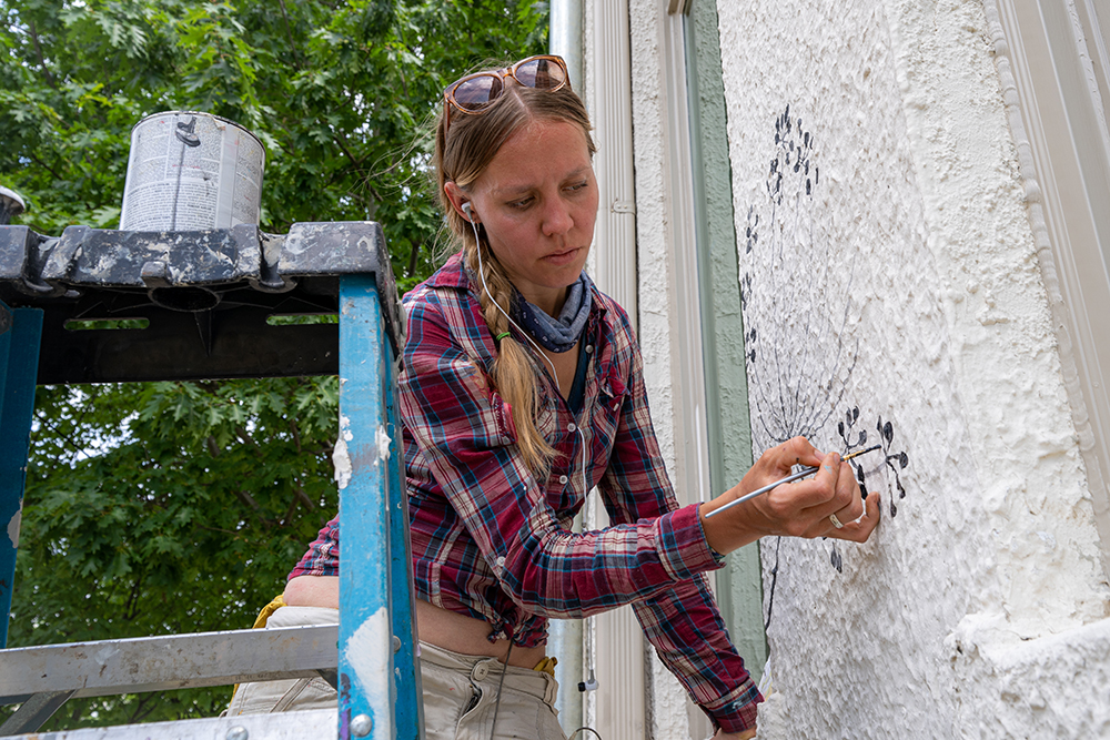 Artist Yulia Avgustinovich paints delicate shapes of leaves and flowers.